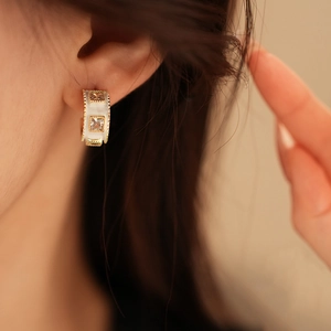 Detail of C-shaped gold plated stud earring with white mother of pearl and cubic zirconia