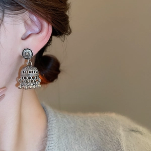 Close-up of vintage silver Jhumka earrings with hollow carvings and beaded tassels