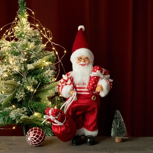Close-up of a 12-inch standing Santa Claus doll with gifts and a lighted Christmas tree