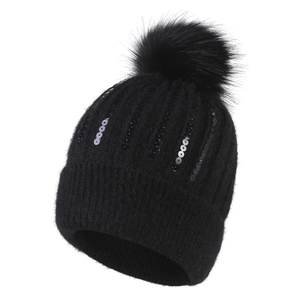 Détail du bonnet en maille noir avec paillettes et pompon en fausse fourrure pour l'hiver