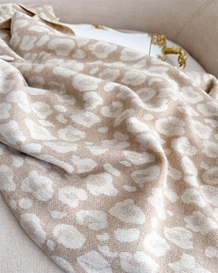 Close-up of soft beige leopard jacquard fabric texture on a fashion scarf with fringes