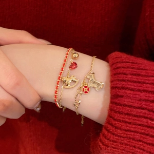 Detail of three-piece gold plated bracelet set with horse charms and red woven cord