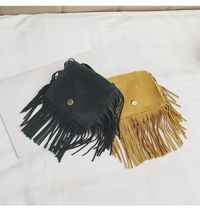 Flat lay of black and ginger yellow leopard fringe crossbody bags on white bedding