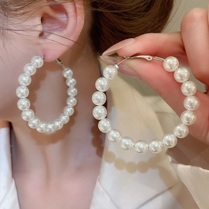 Macro detail of elegant silver needle hoop earrings with white round pearl beads