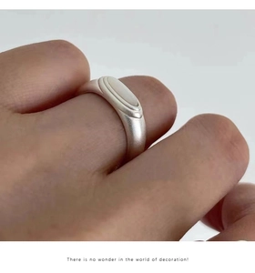 Close-up of matte silver ring with white oval shell inlay on finger