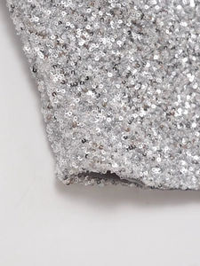 Macro di paillettes argento su tessuto che esaltano la trama metallica lucida