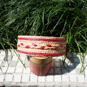 Detailed close-up of handmade beige raffia headband with red woven pattern details
