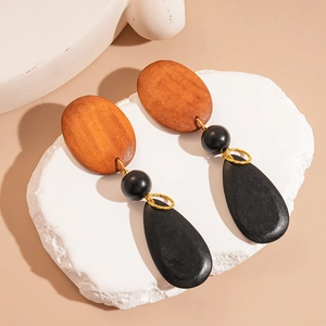 Retro geometric earrings with brown wood oval and black teardrop pendants on a stone base