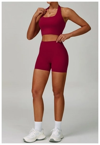Detail of berry red high-waist yoga shorts and halter sports bra with a matte finish