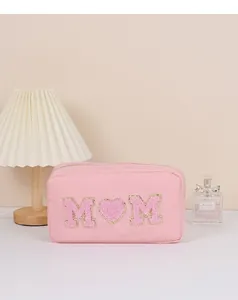Gedetailleerd overzicht van een roze make-uptasje met chenille M en hart-patches