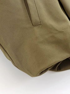 Close-up of olive green bomber jacket featuring twill fabric texture and stitching details
