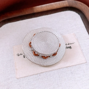 Détail macro de la texture tressée argentée et du ruban brun sur la broche chapeau