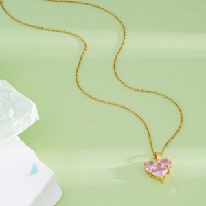 Minimalist 18K gold plated heart necklace with pink crystals on light green background