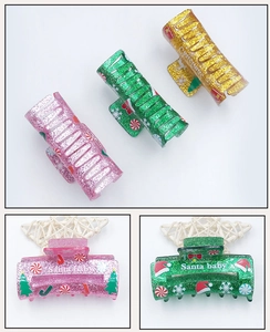 Detailed view of glittery Christmas acrylic hair claws with festive holiday patterns