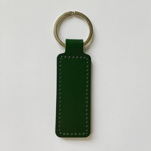Close-up of green PU leather keychain with metal ring and visible double-sided stitching