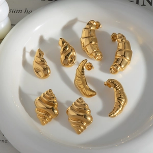 Detailed view of four pairs of gold-plated croissant and conch stud earrings on a plate