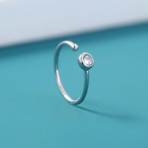 Macro shot of silver U-shaped nose ring with a clear round gemstone and polished ball end