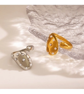 Detailed close-up of pearl-embedded gold and silver rings on textured glass plate