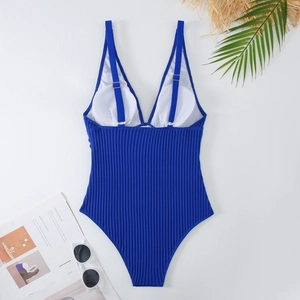 Dettaglio del costume intero blu scuro a costine con scollo a V e accessori da spiaggia
