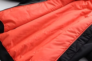 Makroaufnahme des leuchtend orangefarbenen Innenfutters und des schwarzen Bomberjacken-Außenmaterials