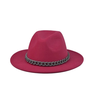 Detail of a rose red felt fedora hat featuring a chunky grey chain decoration