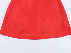 Détail de l'ourlet d'une robe en suédine rouge avec coutures précises et texture mate