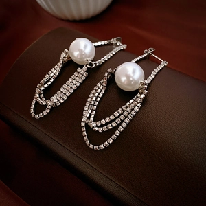 Detailed macro view of long pearl tassel earrings with shimmering diamond-set chains
