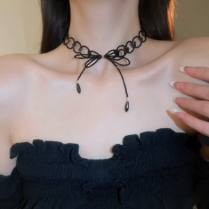 Close-up of black beaded choker featuring a bow design and long droplet pendants