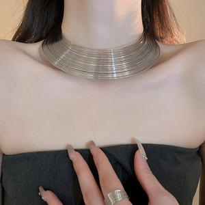 Close-up of layered wide silver choker and matching metal ring on a model's neck and finger