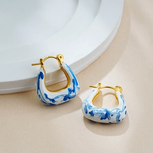 Detail of 18K gold U-shaped hoop earrings with blue and white marble enamel texture