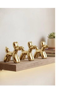 Moderne sculture dorate a forma di cane palloncino su mensola con luce d'ambiente calda
