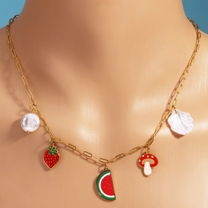 Gold titanium necklace with fruit pendants and pearls on a beige mannequin bust