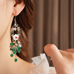 Nahaufnahme von Boho-Quastenohrringen mit grünen Perlen und weißer Blume am Modell