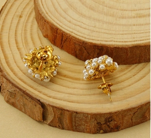 Detail of vintage 18k gold plated sunflower pearl cluster earrings on wooden display