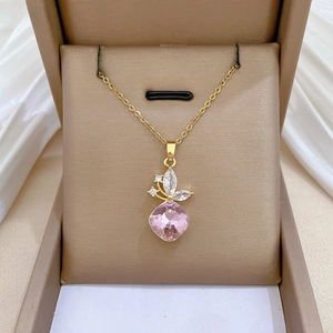 Macro detail of gold butterfly necklace with pink gemstone and white zircon accents