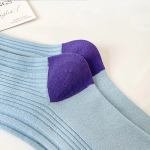 Detail of light blue ribbed knit cotton socks with purple contrasting heel finish