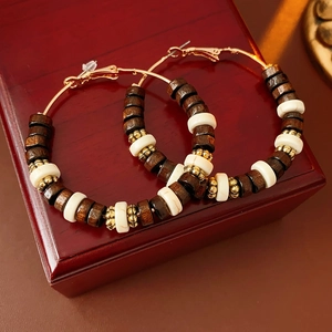 Detailed close-up of bohemian hoop earrings with brown wood and white beads on a red box