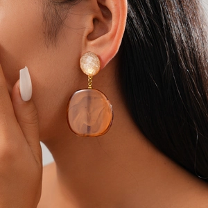 Close-up of vintage resin geometric earrings with gold textured metal and amber pendant