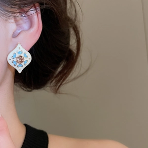Macro detail of a vintage rhombus stud earring with a blue heart and amber gemstone