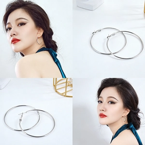 Macro view of silver oversized hoop earrings featuring a polished finish and secure clasp