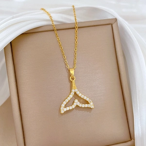 Detailed view of hollow fishtail pendant with sparkling zircons on a gold necklace