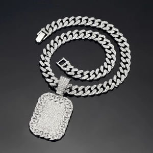 Macro shot of silver-toned hip hop Cuban chain with iced-out rhinestone dog tag pendant