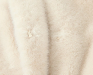 Close-up of fluffy cream faux fur jacket texture and hidden metal hook fastener