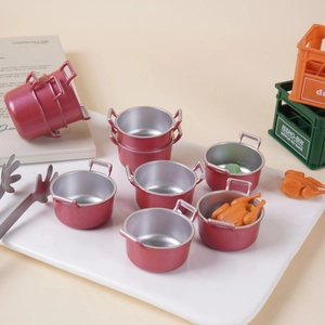 Miniature dollhouse kitchen set with red toy soup pots and tiny cooking accessories