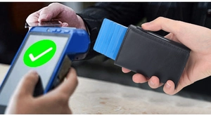 Close-up of black leather RFID wallet showing automatic card ejection near a payment terminal
