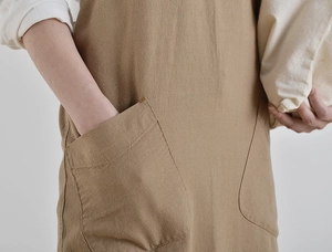 Macro view of khaki linen apron showing large pocket design and clear fabric texture