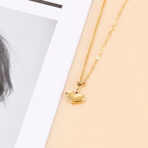 Dettaglio di una collana con ciondolo a cuore dorato e maglie miste su rivista di moda