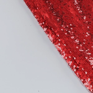 Macro shot of red sequin fabric detailing with shiny metallic reflections for party outfits