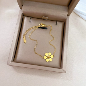 Detail of a golden stainless steel six-petal flower bracelet in a velvet gift box