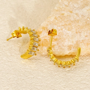 Gold-plated C-shaped earrings with baguette cut zircons displayed on natural stone